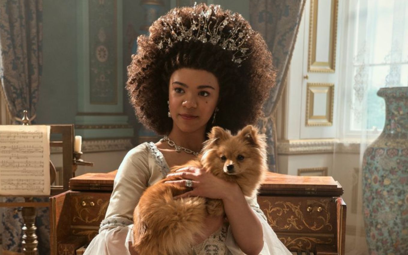 A atriz India Amarteifio segura um cachorro na série Rainha Charlotte, da Netflix
