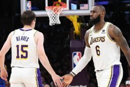 Austin Reaves e LeBron James se cumprimentam em jogo da NBA; eles estão com uniforme branco dos Lakers