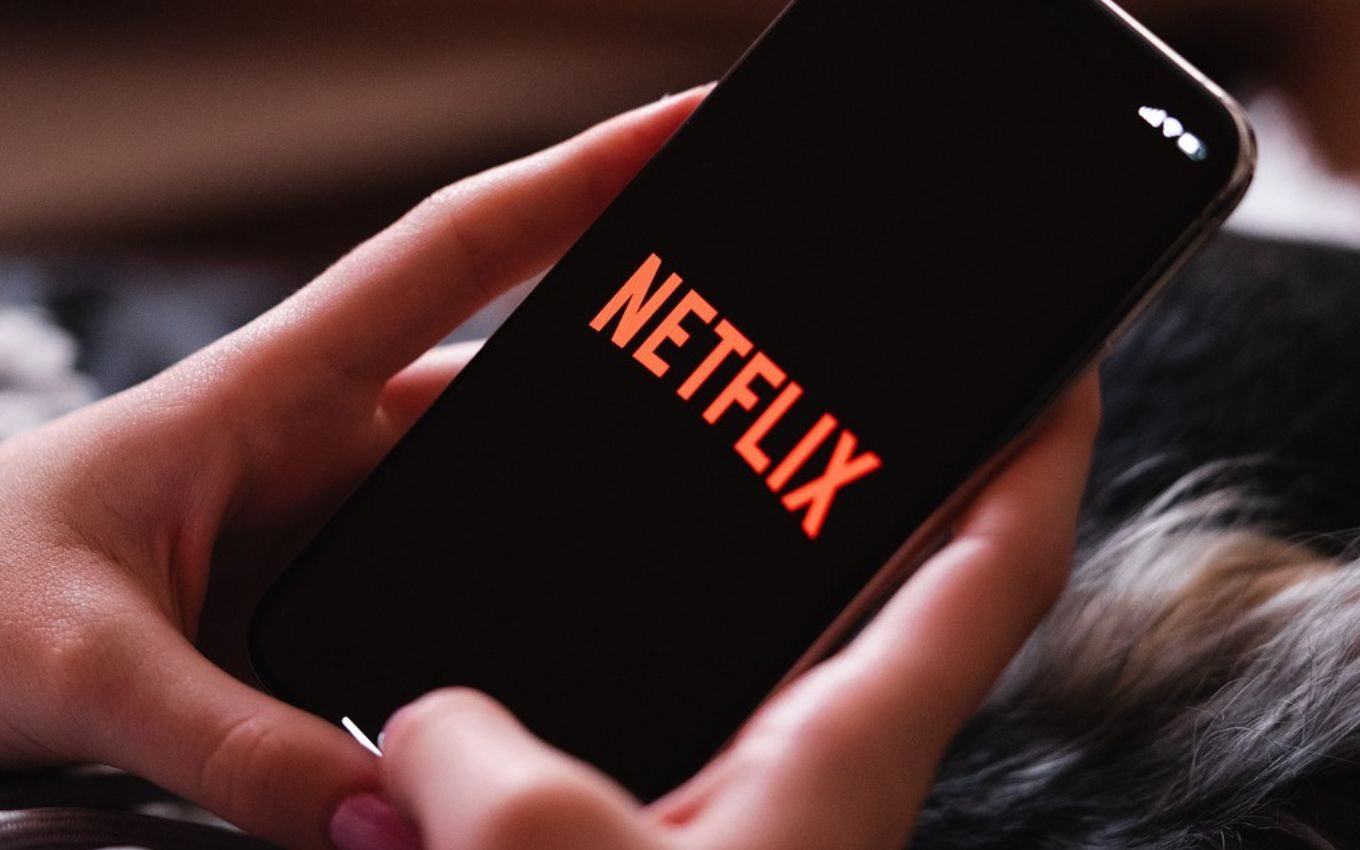 Imagem de Netflix sendo acessada pelo celular: preço do serviço de streaming subiu