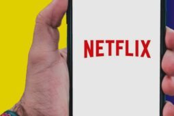 Mão segura o celular com logo da Netflix na tela; conheça planos do serviço de streaming