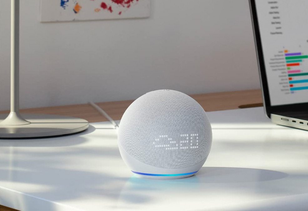 Echo Dot 5a. Geração sobre uma mesa de escritório ao centro, exibindo as informações: ícone de nuvens e a temperatura.