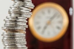 Moedas e relógio ao fundo: foto sobre expediente bancário no Carnaval 2024